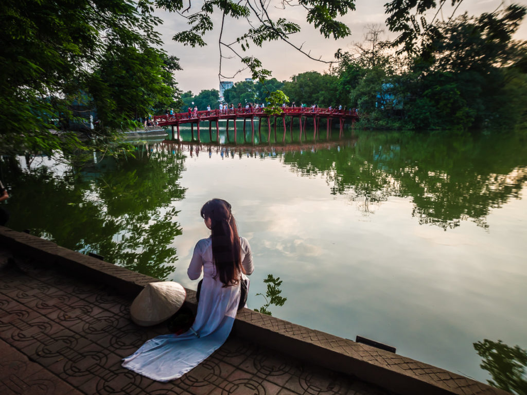 Beautiful Woman With Long Hair In Purple Satin Facing Huc Bridge on Tranquil Hoàn Kiếm Lake