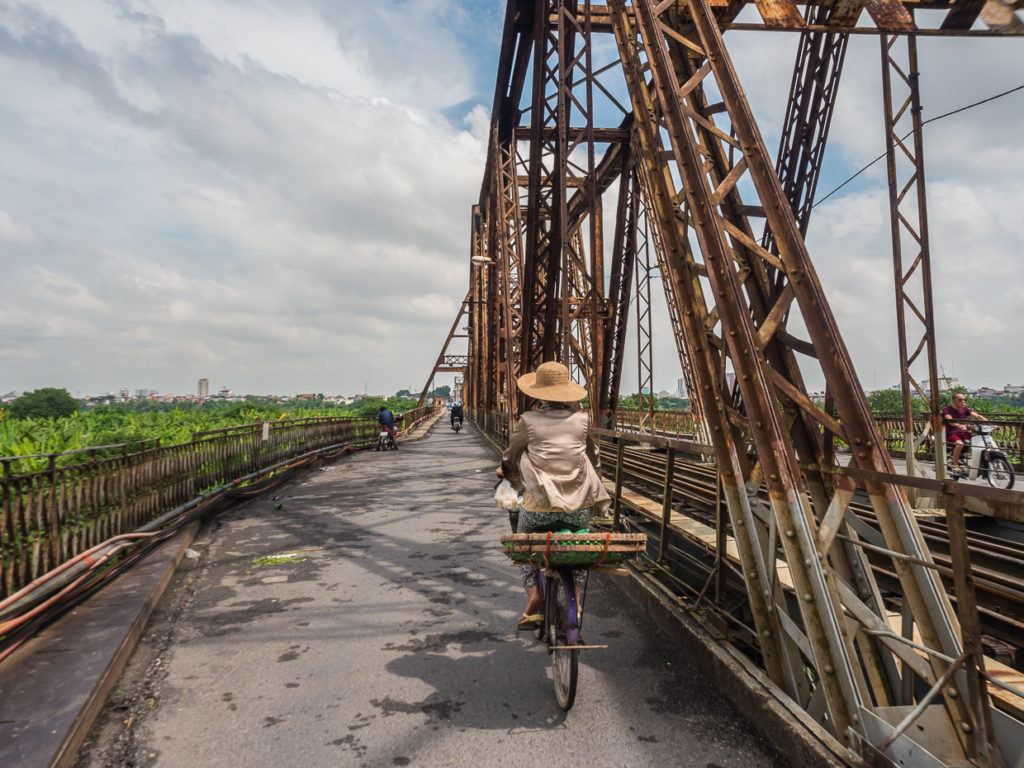 Woman Wearing Hat with Basket Cycling Long Biên Bridge Into A Bright Future