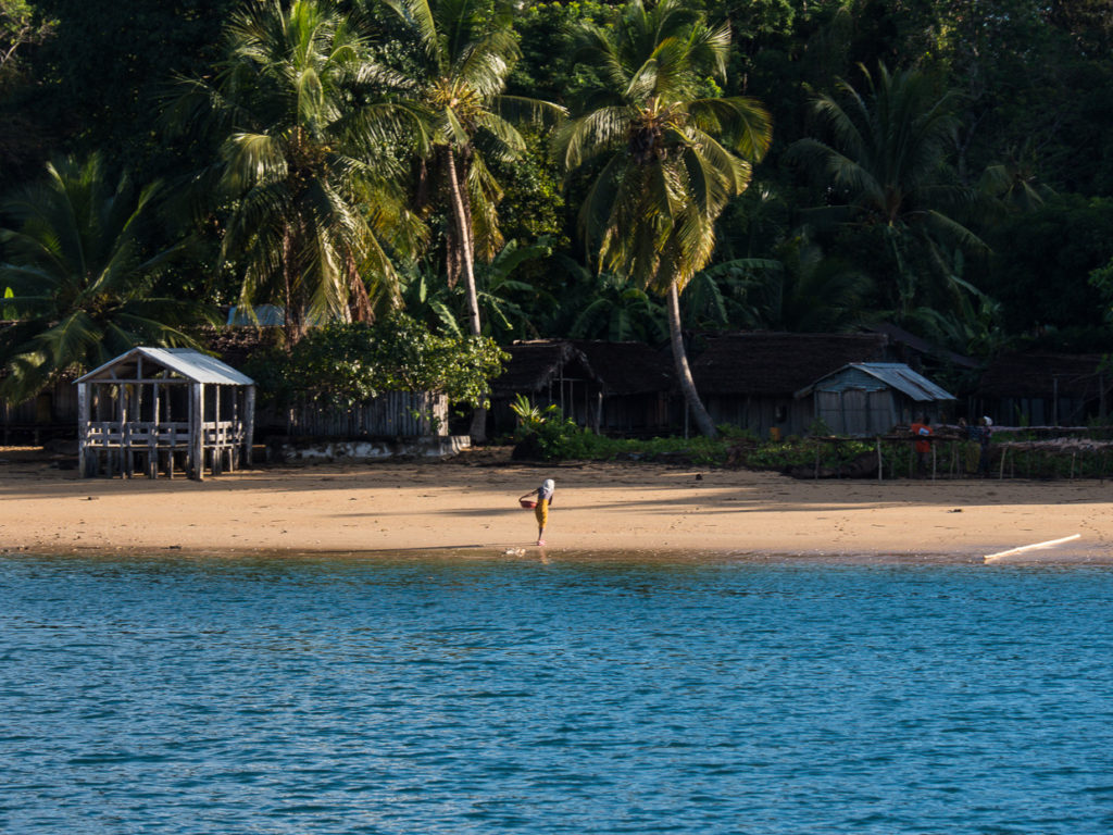 Coastal Village At Nosy Mamoko With Huts And Woman Carrying Laundry From Shore