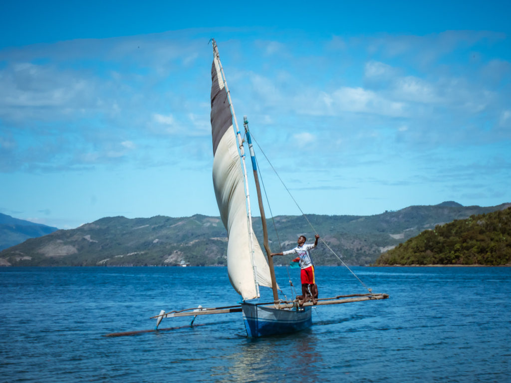 Traditional Boat Under Sail With Man Looking Upward to Top Of Mast
