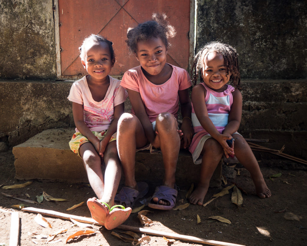 Three children smiling on house porch in Madagascar