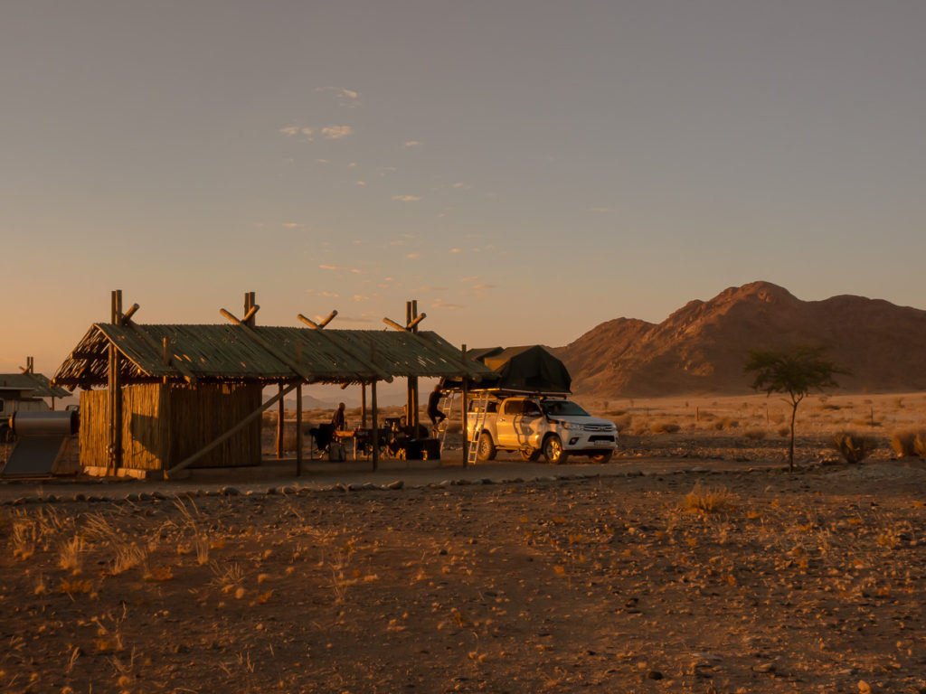 Sossus Oasis Campsite with campers and 4x4 van at sunrise in Sossusvlei Namibia