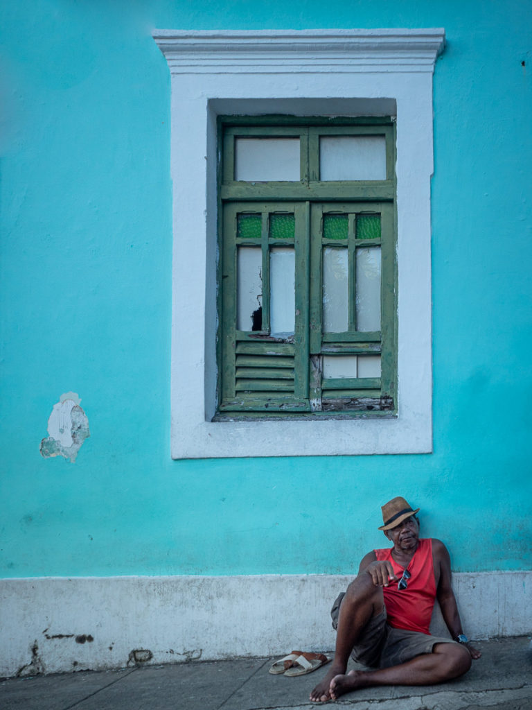 Local Man Sitting Against Blue Building in Olinda