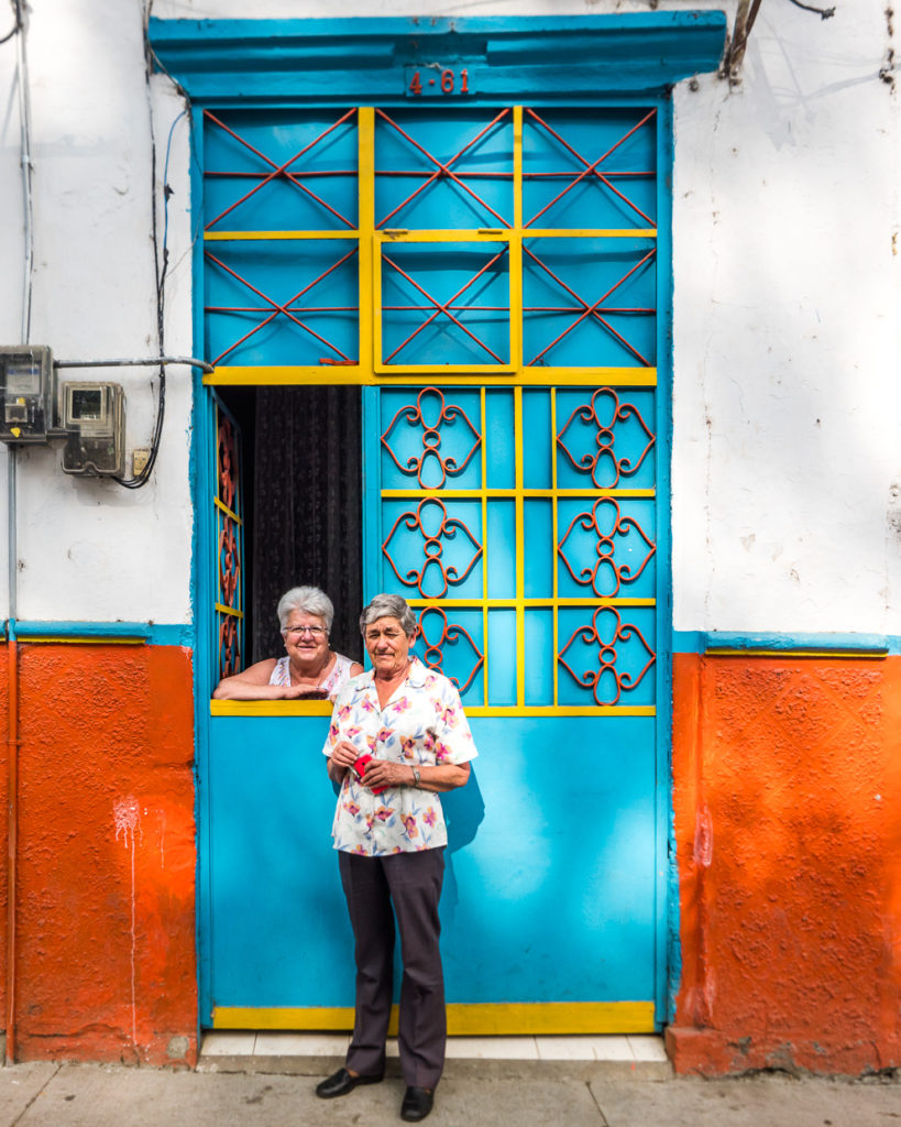 Two women chat window-side on streets of Salamina, Colombia