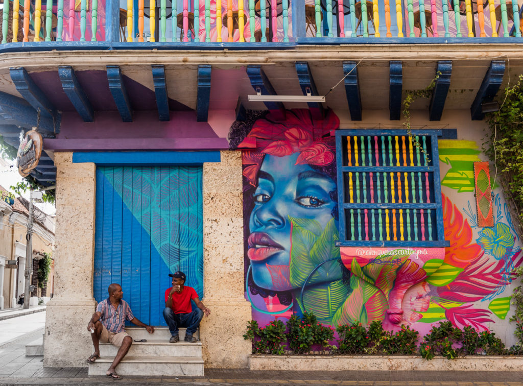Men sitting on porch in front of colorful building in Gestemani